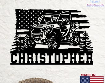 May include: Black metal wall art featuring a side-profile of an off-road vehicle, an American flag, and the name "CHRISTOPHER". The design includes pine trees and stars. The words "MADE IN USA" and a flag are also visible.