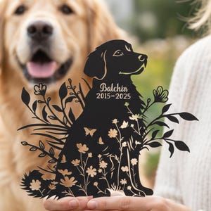 May include: A black metal dog memorial silhouette with floral and butterfly accents. The memorial features the name "Balchin" and the years "2015-2025". The dog is a golden retriever.