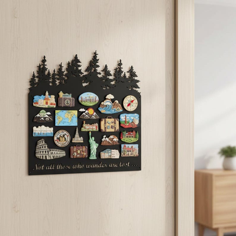 May include: Black metal wall decor featuring a silhouette of trees at the top and a rectangular frame holding travel-themed magnets. The magnets depict landmarks, maps, and travel imagery. The quote "Not all those who wander are lost..." is at the bottom.