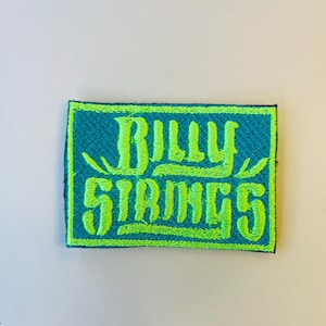 May include: A green and blue embroidered patch with the text "Billy Strings" in a stylized font.