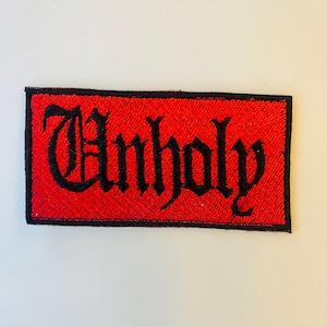 May include: A red embroidered patch with black stitching that says "Unholy" in a gothic font.