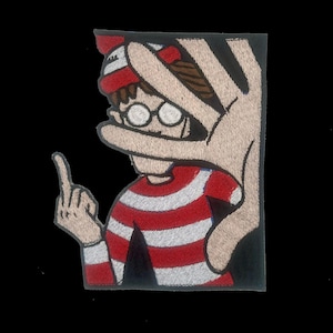 May include: Embroidered patch featuring a cartoon character in a red and white striped shirt and hat, wearing glasses, and giving the middle finger. A large hand covers part of the character's face.