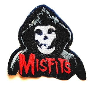May include: Embroidered patch featuring the Misfits' Crimson Ghost skull logo. The patch is black with a white skull and red text that reads "MISFITS". The patch has a hood and a white border.