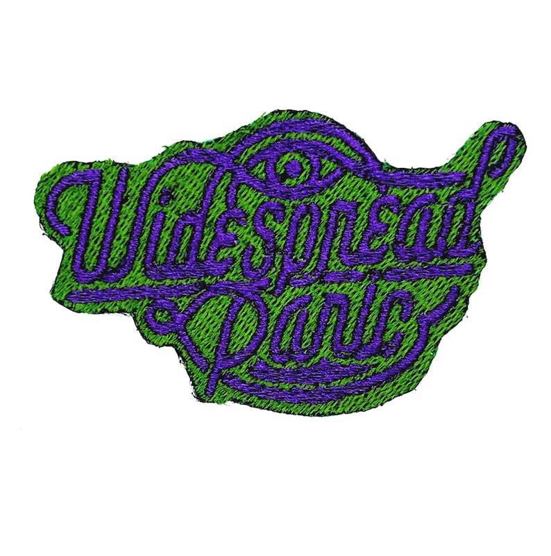 Może przedstawiać: Haftowana naszywka z napisem "Widespread Panic" w fioletowym skrypcie na zielonym tle. Naszywka ma unikalny kształt i zawiera wz&oacute;r oka nad tekstem.