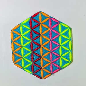 May include: A turquoise, hexagon-shaped patch with a colorful embroidered design. The design features overlapping flower-like patterns in red, orange, pink, and yellow. The patch has a bright green border.