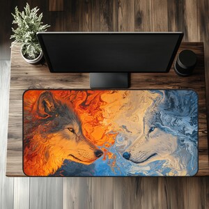 May include: Rectangular mouse pad featuring a vibrant design of two wolf faces, one in fiery orange and the other in cool blue tones. The artwork has a marbled effect, creating a dynamic and artistic look. The mouse pad is placed on a wooden desk.