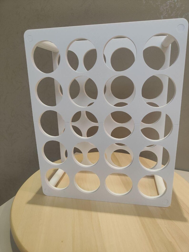 Puede incluir: Un organizador rectangular blanco con m&uacute;ltiples aberturas circulares. El organizador est&aacute; hecho de un material s&oacute;lido y est&aacute; dise&ntilde;ado para contener objetos. Se coloca sobre una superficie de madera de color claro.