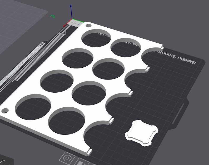 Puede incluir: Una bandeja rectangular blanca impresa en 3D con m&uacute;ltiples recortes circulares. La bandeja tiene un patr&oacute;n de rejilla y una peque&ntilde;a pieza cuadrada al lado. El fondo es una superficie gris oscuro.