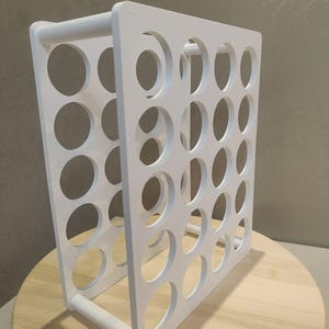 Puede incluir: Un organizador blanco de marco abierto con m&uacute;ltiples aberturas circulares. La estructura es rectangular con una barra en forma de asa en la base. El organizador est&aacute; dise&ntilde;ado para contener m&uacute;ltiples art&iacute;culos. El art&iacute;culo est&aacute; sobre una superficie de madera.