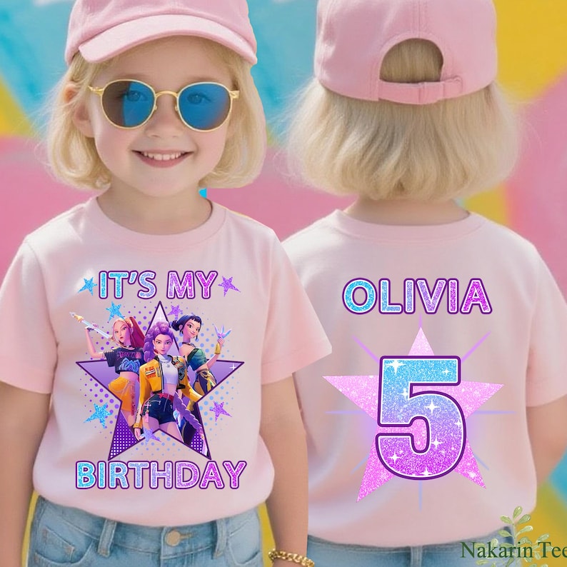 May include: A light pink t-shirt with the text "IT'S MY BIRTHDAY" and a graphic of three animated characters inside a star. The back of the shirt has the name "OLIVIA" and the number "5" in a starburst design. The child is wearing a pink cap and sunglasses.