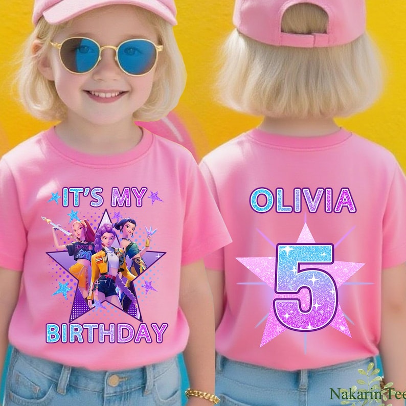 May include: Pink t-shirts with a birthday theme. The front of the shirt says "IT'S MY BIRTHDAY" with a star graphic and cartoon characters. The back of the shirt says "OLIVIA" and the number "5" in a star graphic.