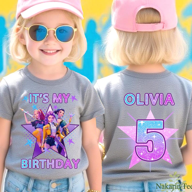 May include: A gray t-shirt with the text "IT'S MY BIRTHDAY" and a graphic of three cartoon characters on the front. The back of the shirt has the name "OLIVIA" and the number "5" on a star. The shirt is worn by a child.