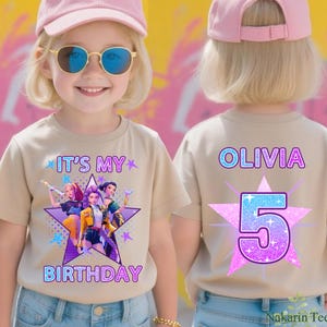 May include: A beige t-shirt with a graphic design featuring a star and the text "IT'S MY BIRTHDAY". The front design includes illustrations of three characters. The back of the shirt displays the name "OLIVIA" and the number "5".