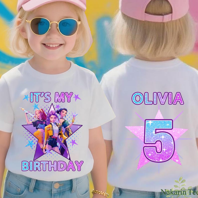 May include: White t-shirt with the text "IT'S MY BIRTHDAY" and a graphic of three cartoon characters inside a purple star. The back of the shirt has the name "OLIVIA" and the number "5" in a star design.