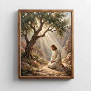 Puede incluir: Una pintura enmarcada representa una figura arrodillada bajo un árbol, bañada por la luz del sol. La obra presenta un paisaje sereno con una figura vestida con túnicas blancas, sobre un fondo de rocas y follaje. El marco es de madera.