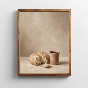 Könnte beinhalten: Gerahmtes Gemälde, das ein Brot mit einem Bissen, Krümeln und einer kleinen Tasse zeigt. Das Brot ist hellbraun und die Tasse hat eine gedämpfte Terrakottafarbe. Der Hintergrund ist ein weiches, neutrales Beige.