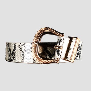 Peut inclure: Une ceinture blanche à motif peau de serpent avec une boucle dorée.