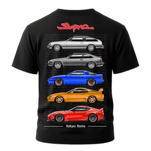 Puede incluir: Camiseta negra con la palabra "Supra" en rojo y ilustraciones de coches Toyota Supra en plata, gris, azul, naranja y rojo. El texto "Tokyo Toms" está impreso debajo.