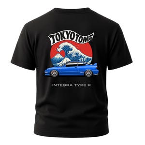 May include: Black t-shirt featuring a blue Integra Type R car graphic. The design includes a red sun, a white wave, and the text "TOKYO TOMS" above the car. The text "INTEGRA TYPE R" is below the car.