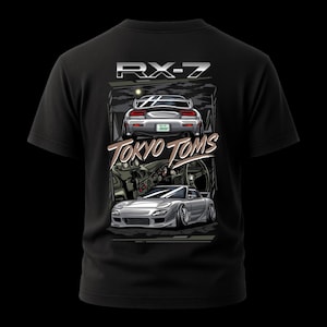 Könnte beinhalten: Schwarzes T-Shirt mit einer Grafik eines silbernen Sportwagens, dem Text "RX-7" und "Tokyo Toms". Das Design beinhaltet eine Illustration des Innen- und Außenbereichs des Autos.