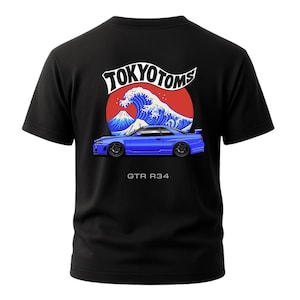May include: Black t-shirt featuring a blue sports car graphic with the text "GTR R34" below it. The design includes a red circle, a blue wave, and the text "TOKYO TOMS" in a white banner.