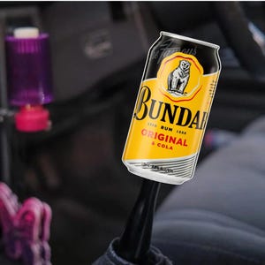 May include: A Bundaberg Rum Original & Cola can with a yellow and black design. The can features a bear logo and the text "Bundaberg Rum Original & Cola". The can is 375ml and 4.6% ALC/VOL.