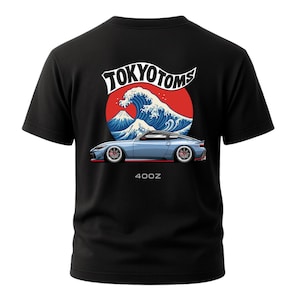 May include: Black t-shirt featuring a graphic of a blue sports car with red accents, set against a red circle with a wave and mountain design. The text "TOKYOTOMS" and "400Z" are also visible.