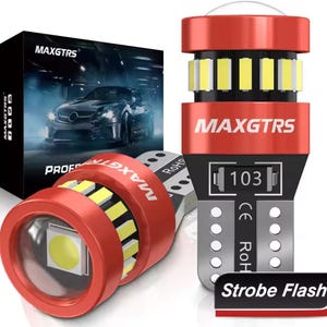 Puede incluir: Bombillas LED rojas y plateadas para coche con el texto "MAXGTRS". Las bombillas emiten una luz blanca brillante y están empaquetadas en una caja negra con un gráfico de coche. El texto "Strobe Flash" está en una etiqueta roja y negra.