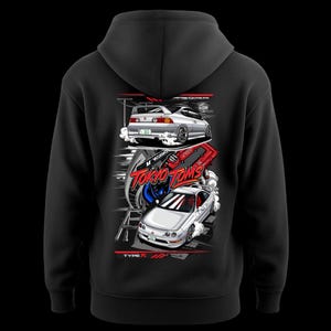 May include: Black hooded sweatshirt featuring a graphic of two silver sports cars with the text "TOKYO TOMS" and "TYPE R". The design includes red and white accents, and a stylized background.