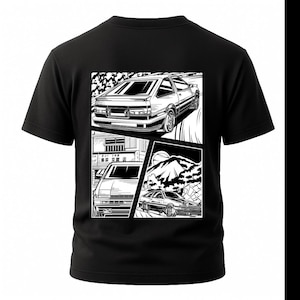 May include: Black t-shirt featuring a black and white graphic of a car in a comic book style. The graphic includes three panels with different views of the car, set against a mountain and road background.