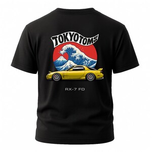May include: Black t-shirt featuring a yellow sports car design with the text "TOKYO TOMS" above a wave and mountain graphic. The text "RX-7 FD" is below the car.