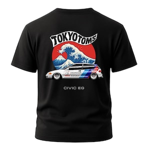 Könnte beinhalten: Schwarzes T-Shirt mit einer Grafik eines weißen Honda Civic EG-Autos, mit einem blauen und roten Design, vor einem roten Sonnen- und Wellenhintergrund. Der Text "TOKYO TOMS" und "CIVIC EG" sind ebenfalls sichtbar.