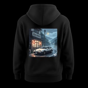 Könnte beinhalten: Schwarzer Kapuzenpullover mit einer Grafik eines weißen Sportwagens auf einer nassen Straße vor einem japanischen Restaurant. Das Auto trägt den Text "Initial D". Das Restaurant hat japanischen Text und rote Laternen.