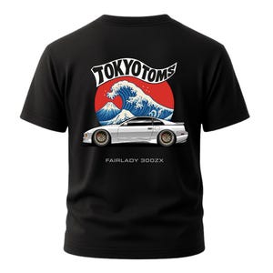 May include: Black t-shirt featuring a graphic of a white Fairlady 300ZX car with a Japanese wave design and the text "TOKYO TOMS". The design includes a red sun and a mountain.