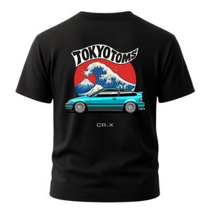 May include: Black t-shirt with a teal CR-X car graphic, Japanese wave, and mountain design. The text "TOKYO TOMS" is above the car, and "CR-X" is below.