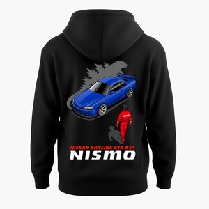 May include: Black hooded sweatshirt featuring a blue Nissan Skyline GTR R34 car graphic with a driver in red racing gear. The text "NISSAN SKYLINE GTR R34 NISMO" is printed in white. The design is on the back of the sweatshirt.