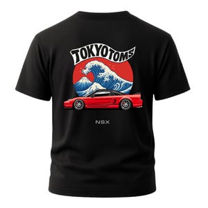 May include: Black t-shirt featuring a red sports car design with the text "NSX" at the bottom. The graphic includes a red circle, a blue wave, and the text "TOKYOTOMS" in white.