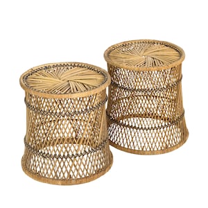 May include: Two natural woven rattan stools. The stools have a round top and a flared base. The sides are woven in a diamond pattern and are held together with dark brown trim. The tops have a circular woven design.