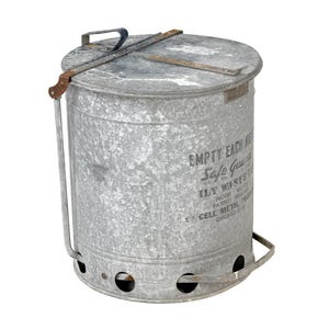 May include: A galvanized metal trash can with a lid and handle. The can has the text "EMPTY EACH" and "Safe Guard" printed on the side. It features a handle for carrying and air holes near the bottom. The can is cylindrical and has a distressed finish.