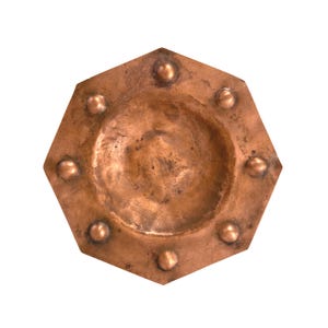 May include: A hexagonal copper tray with a hammered texture and a central circular depression. The flat rim features eight evenly spaced raised copper spheres or studs around the perimeter, creating a distinct geometric and metallic appearance.