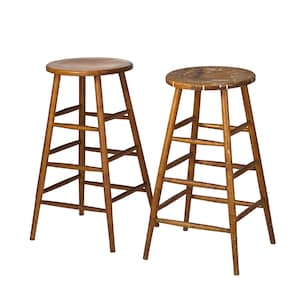 May include: Two tall wooden stools with round seats and four legs connected by horizontal rungs. The stools feature a medium brown wood finish with visible grain and signs of wear on the seat surfaces, including light scratches and scuffs.