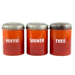 May include: A set of three ceramic mugs with a speckled, matte finish. The mugs are in shades of cream, light brown, and dark brown. Each mug has a simple, minimalist design and a rounded handle. The mugs are likely for coffee or tea.