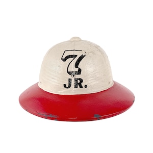 May include: A vintage-style hat with a white crown and a red brim. The crown features the number "7" and the letters "JR." in black. The hat has a slightly distressed appearance, suggesting it is an antique or a replica.