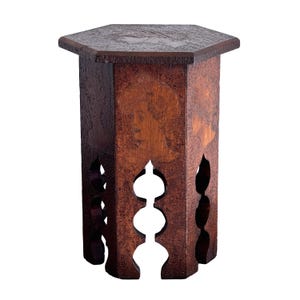May include: A hexagonal wooden side table with a dark brown finish. The table features a flat top and six vertical panels, each decorated with an inlaid profile portrait of a person. The base of each panel has a cutout design with three circular openings.