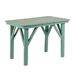 May include: A small, rectangular, distressed-look table painted in a muted teal color. The table has four legs with angled supports and a slightly weathered surface, suggesting an antique or rustic aesthetic. The table measures approximately 12 inches long.