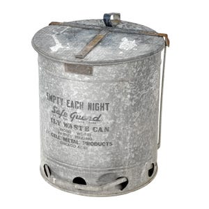 May include: A vintage galvanized steel waste can with a lid and handle. The can features the text "EMPTY EACH NIGHT Safe Guard" and "ILY WASTE CAN". The model number is WC-12, and it was made by Cell Metal Products in Chicago, IL.