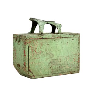 May include: A vintage, rectangular wooden box with a weathered, distressed appearance. The box is painted in a faded green with visible red undertones and a metal handle. The box has a hinged lid and is likely used for storage.