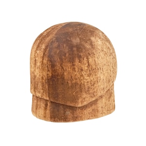 May include: A handcrafted, wooden hat block with a rounded top and a rectangular base. The hat block is made of light brown wood with visible grain and texture. The hat block is used for shaping hats.