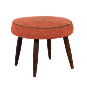 May include: A round stool featuring a textured, burnt orange fabric seat with a dark brown trim along the edge. The seat is supported by four tapered, dark brown wooden legs that angle outward from the center, providing a stable base for the furniture.