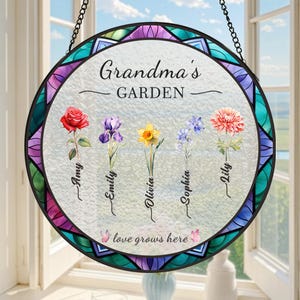 May include: A round stained glass window hanging with a colourful design. The text "Grandma's Garden" is at the top.  Five flowers are depicted with names below each: Amy, Emily, Olivia, Sophia, and Lily. The text "love grows here" is at the bottom.